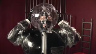 金发女孩穿着黑色乳胶紧身连衣裤,全包裹在充气橡胶和全身塑料套装中